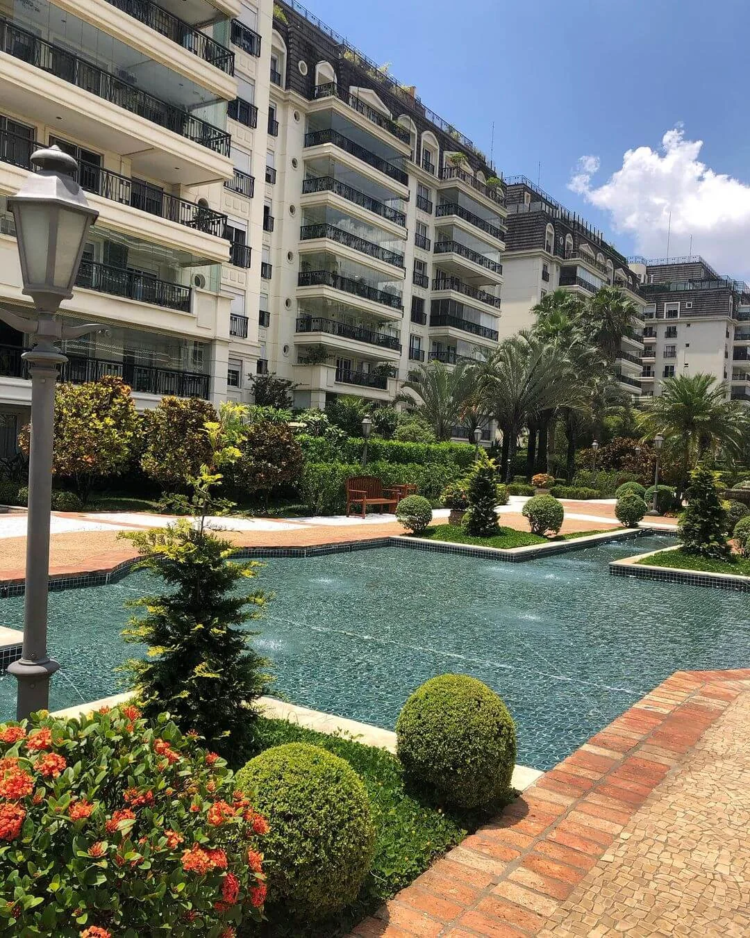 Paisagismo de condomínio com piscina e canteiros ornamentais